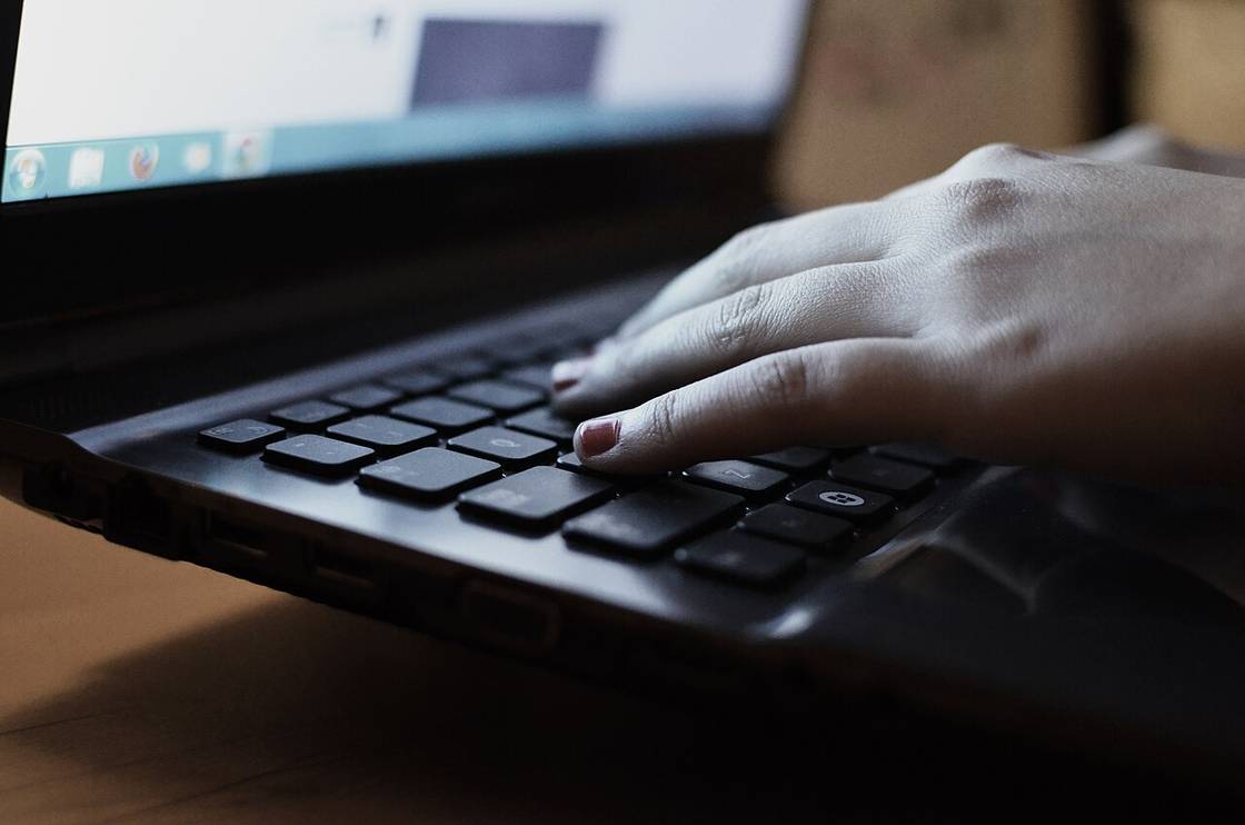 Seseorang mengetik di laptop sambil membaca informasi online